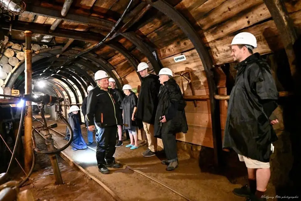 Gruppe mit Helmen bei einer Führung im Besucherbergwerk Hühn in Trusetal, unter Tage im historischen Stollen.