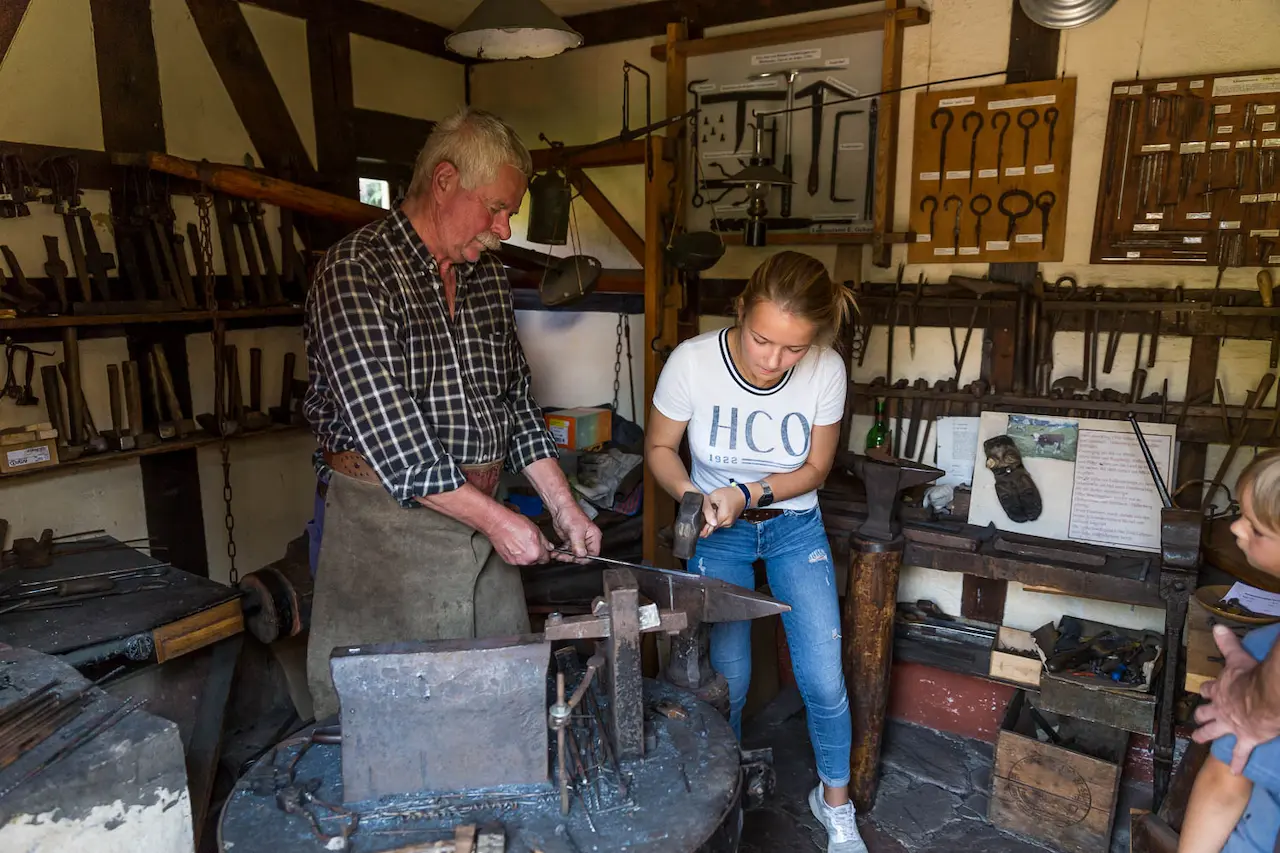 Mann und Frau schmieden im Korkenzieher- und Handwerksmuseum Steinbach-Hallenberg.