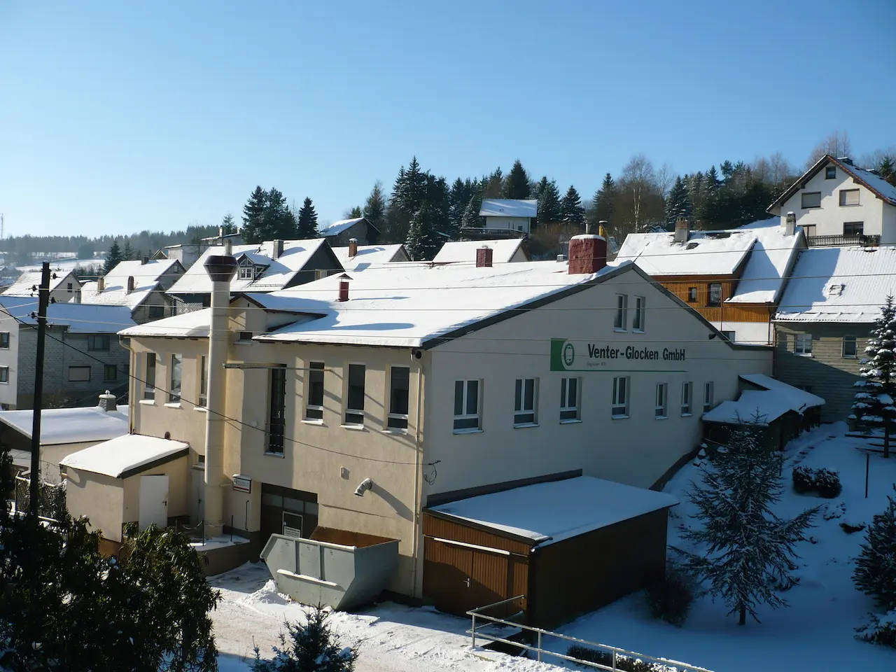 Venter-Glocken GmbH in Floh-Seligenthal im Winter, schneebedecktes Werksgebäude und umliegende Häuser im Thüringer Wald.